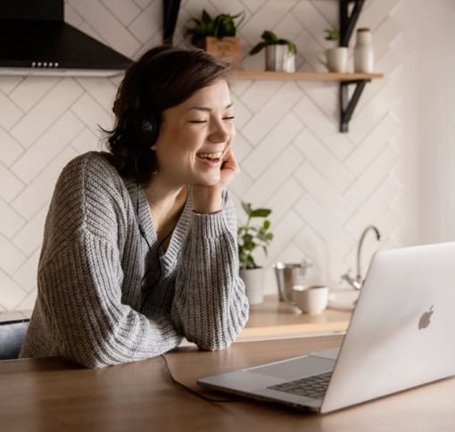 a woman smiling while looking at her laptop screen